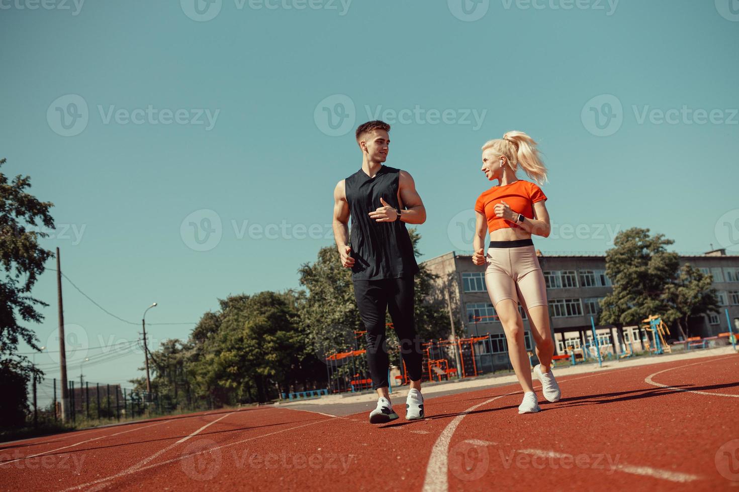 joven pareja deportiva corriendo en el estadio en la pista de atletismo foto