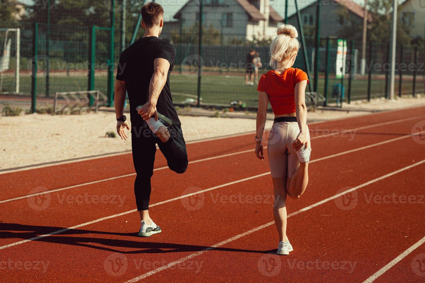 girl and a guy doing a warm-up before sports exercises at the school stadium photo