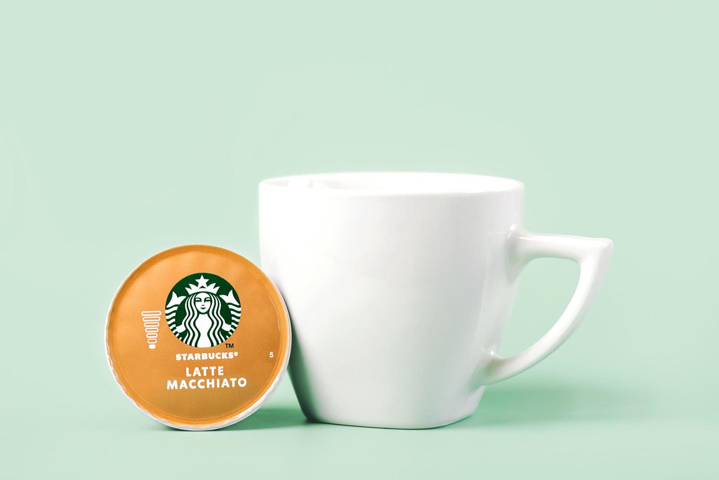 Starbucks latte Macchiato coffee capsule next to white cup of coffee photo