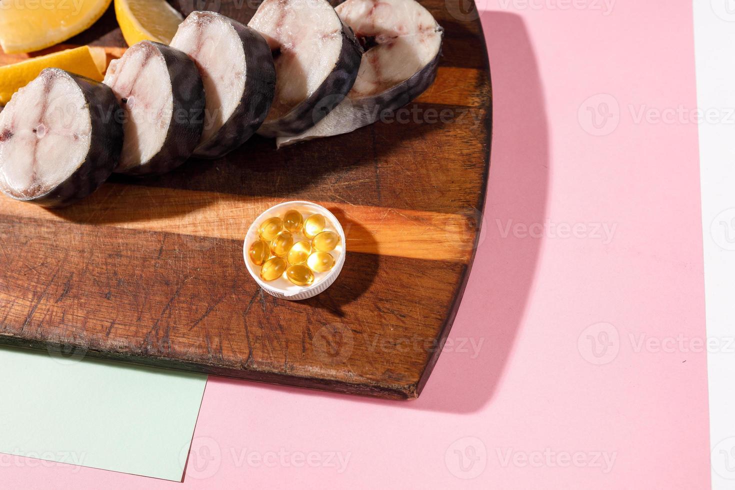 Fresh chopped mackerel lies on a kitchen board along with cod-liver oil capsules photo