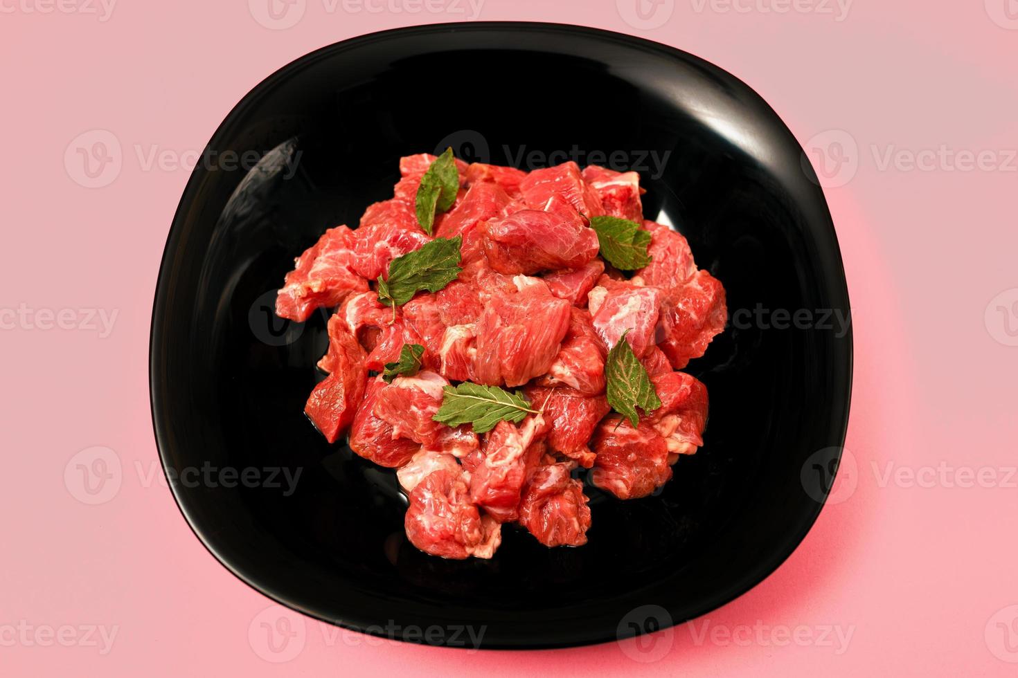 pork chopped into small pieces in a black plate on a bright colored background photo
