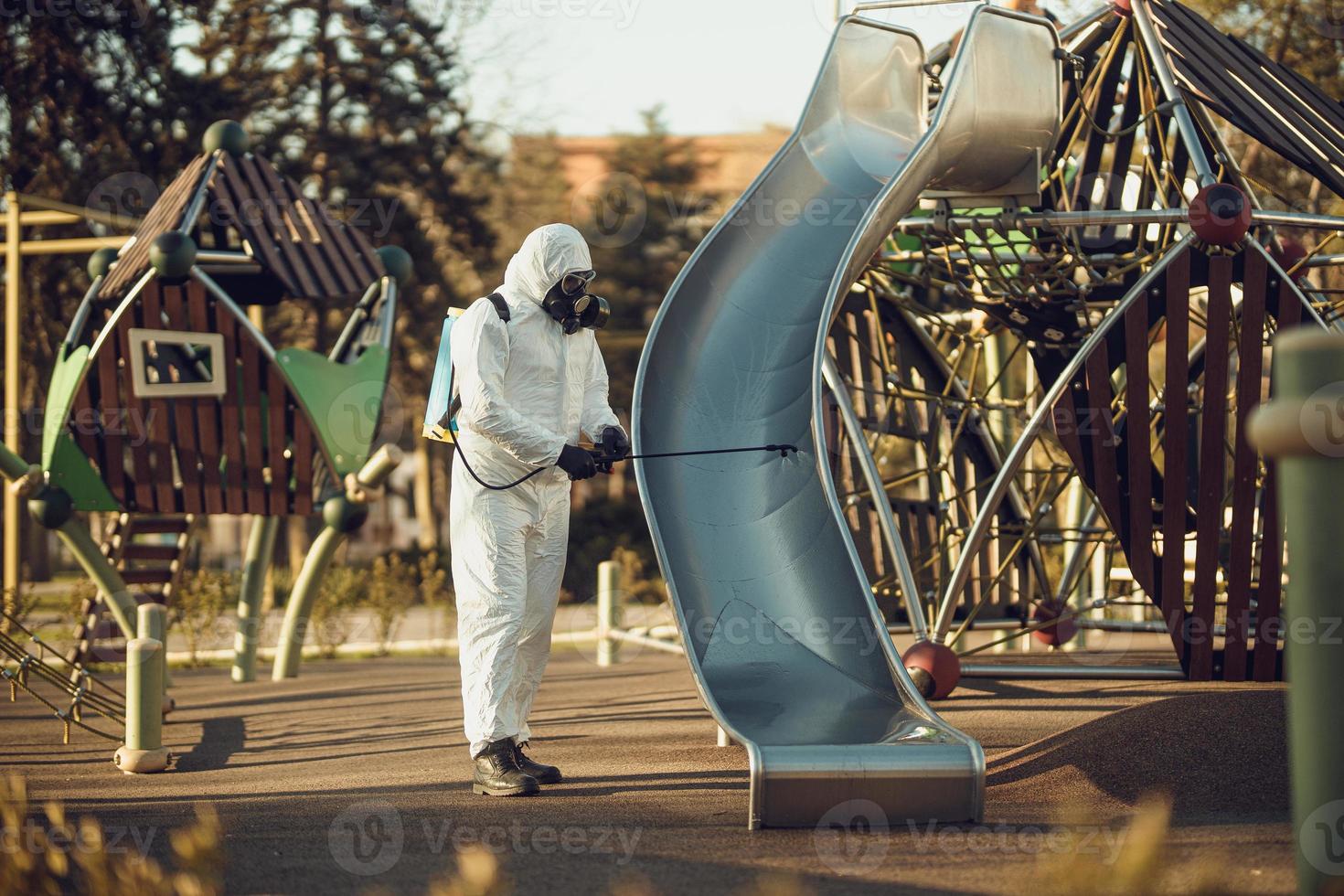 Cleaning and Disinfection on the playground in the sity complex amid the coronavirus epidemic Teams for disinfection efforts Infection prevention and control of epidemic Protective suit and mask photo