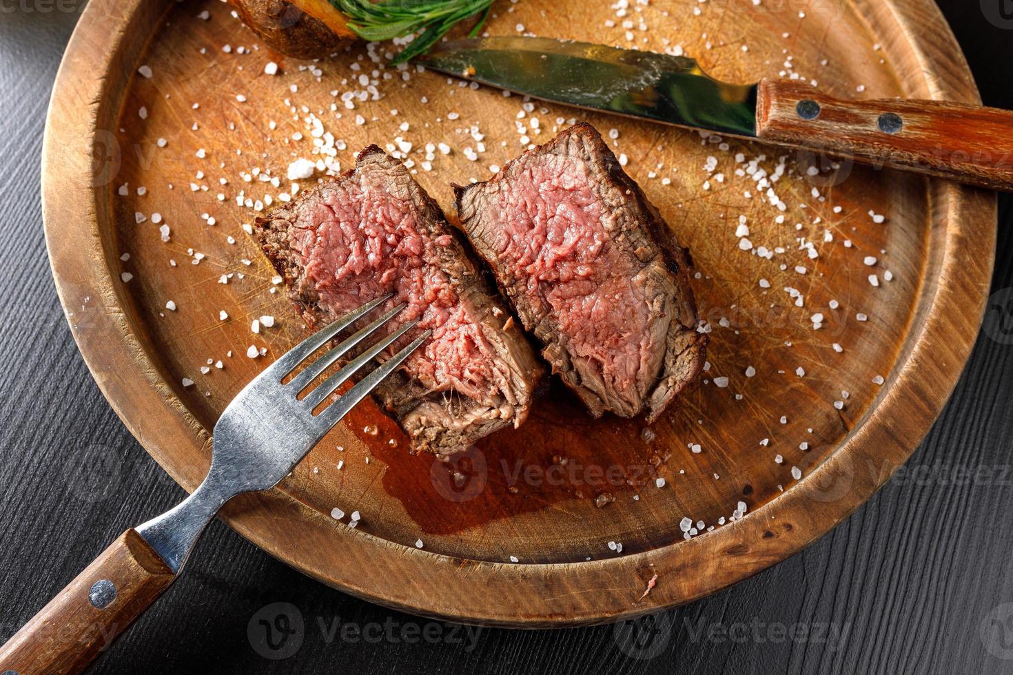 filet mignon medium rare served on a wooden plate with baked potatoes photo