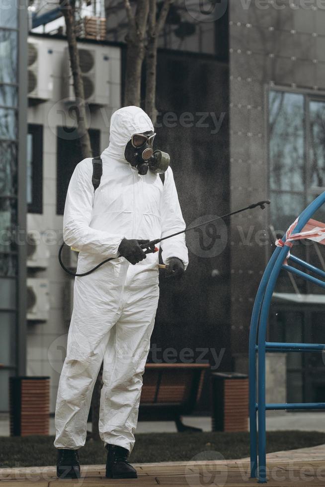 Cleaning and Disinfection on the playground in the sity complex amid the coronavirus epidemic Teams for disinfection efforts Infection prevention and control of epidemic Protective suit and mask photo