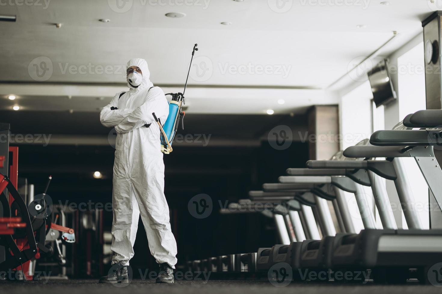 limpieza y desinfección en lugares concurridos en medio de la epidemia de coronavirus limpieza y desinfección de gimnasios prevención de infecciones y control de epidemias. traje de protección y máscara y bolsa de spray foto