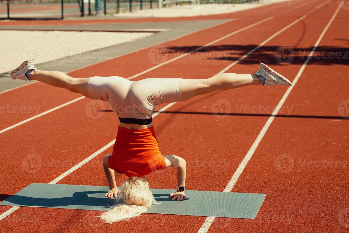 joven rubia aprende a mantener el equilibrio en una parada de cabeza y de manos foto