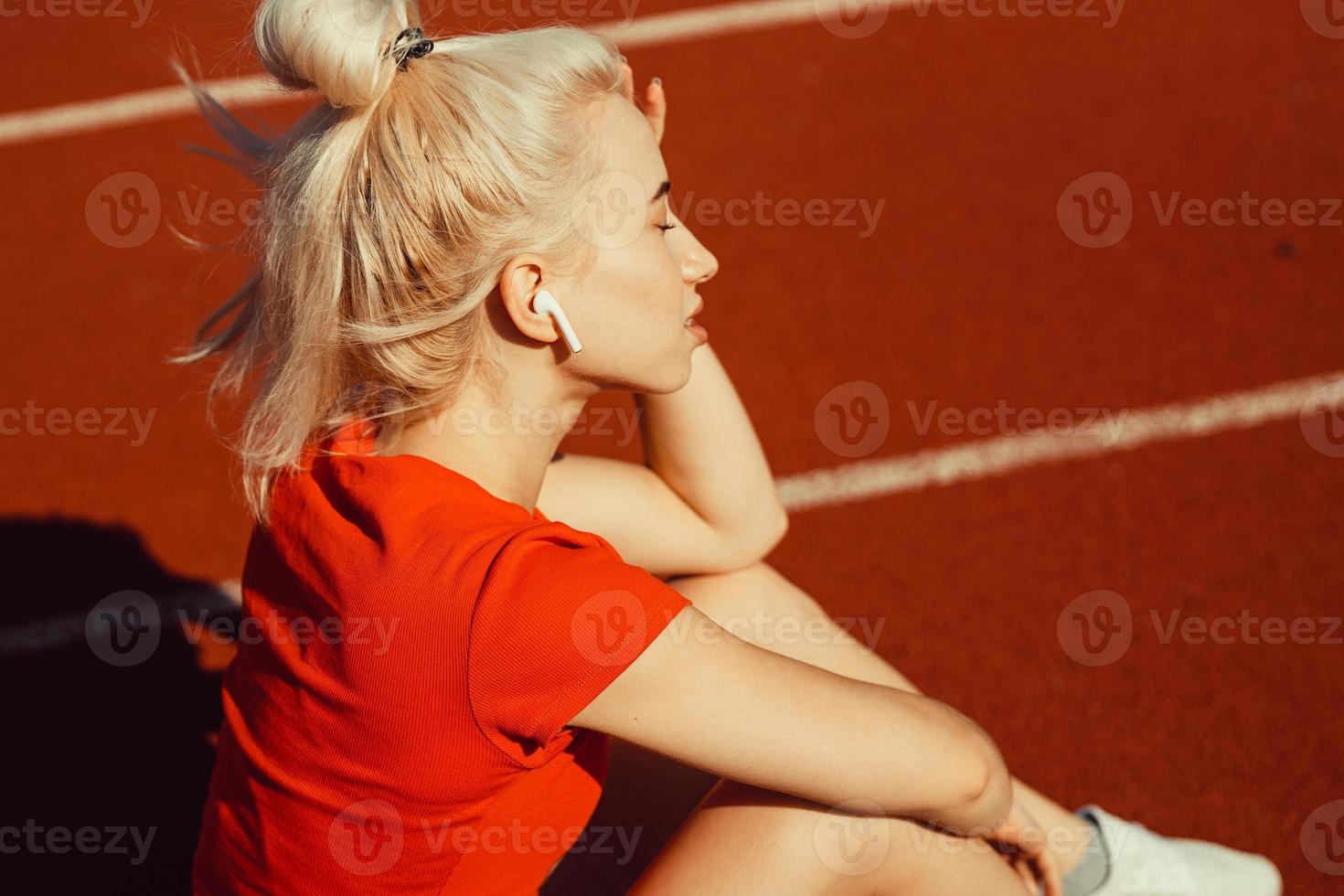 young beautiful girl doing warm-up before sports exercise at school stadium photo