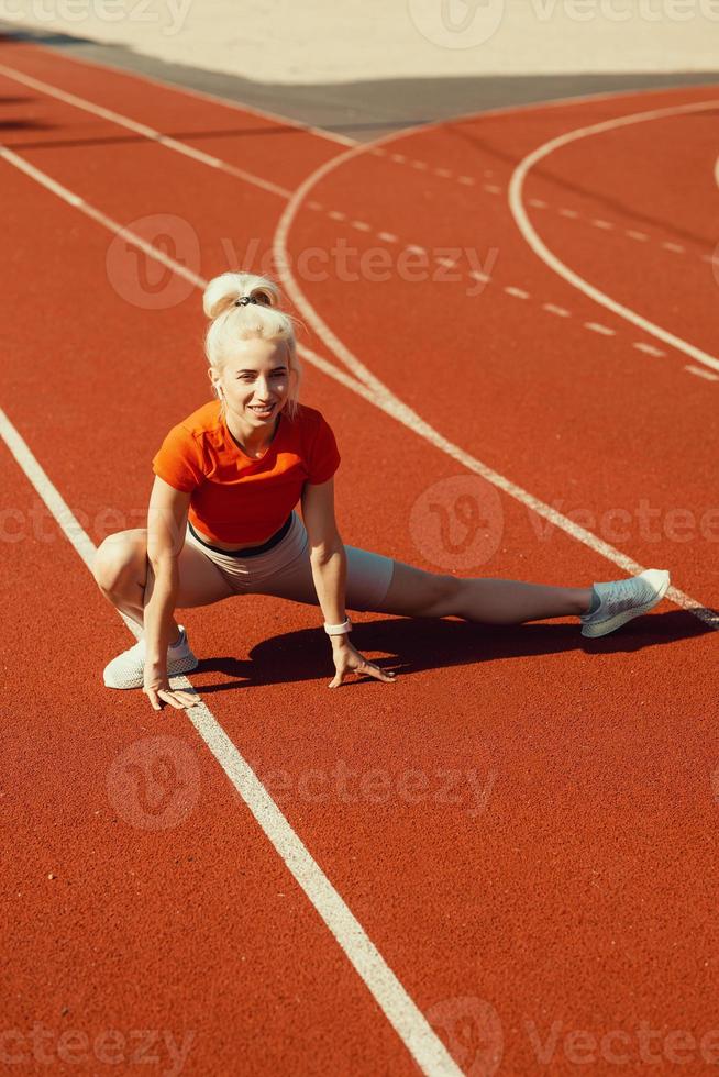 hermosa jovencita haciendo calentamiento antes del ejercicio deportivo en el estadio escolar foto