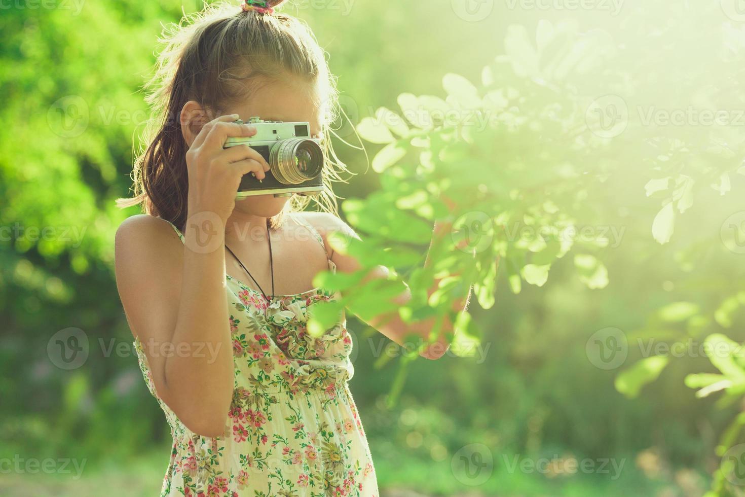 fotógrafo principiante. una niña pequeña toma fotos de un árbol en su cámara de fotos de película