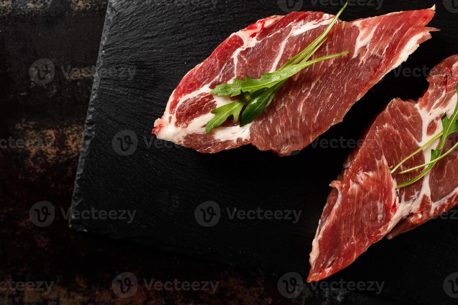 raw pork with spices for cooking on a fire or oven on a dark stone background photo