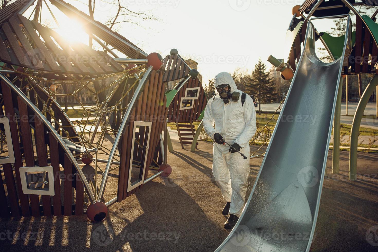 Cleaning and Disinfection on the playground in the sity complex amid the coronavirus epidemic Teams for disinfection efforts Infection prevention and control of epidemic Protective suit and mask photo