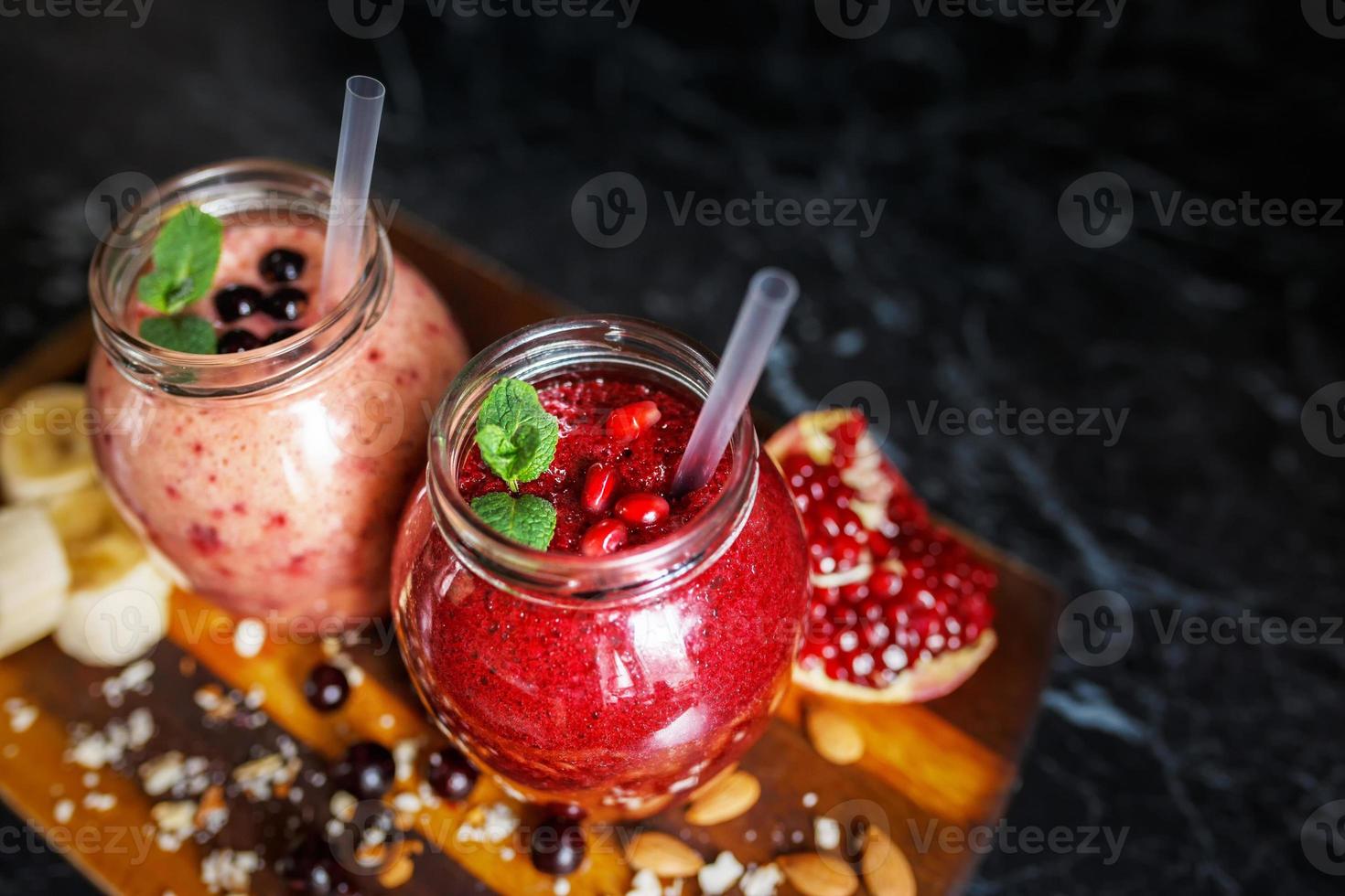 batidos recién preparados de plátano con granada y plátano con mora en botella. dieta, estilo de vida saludable foto