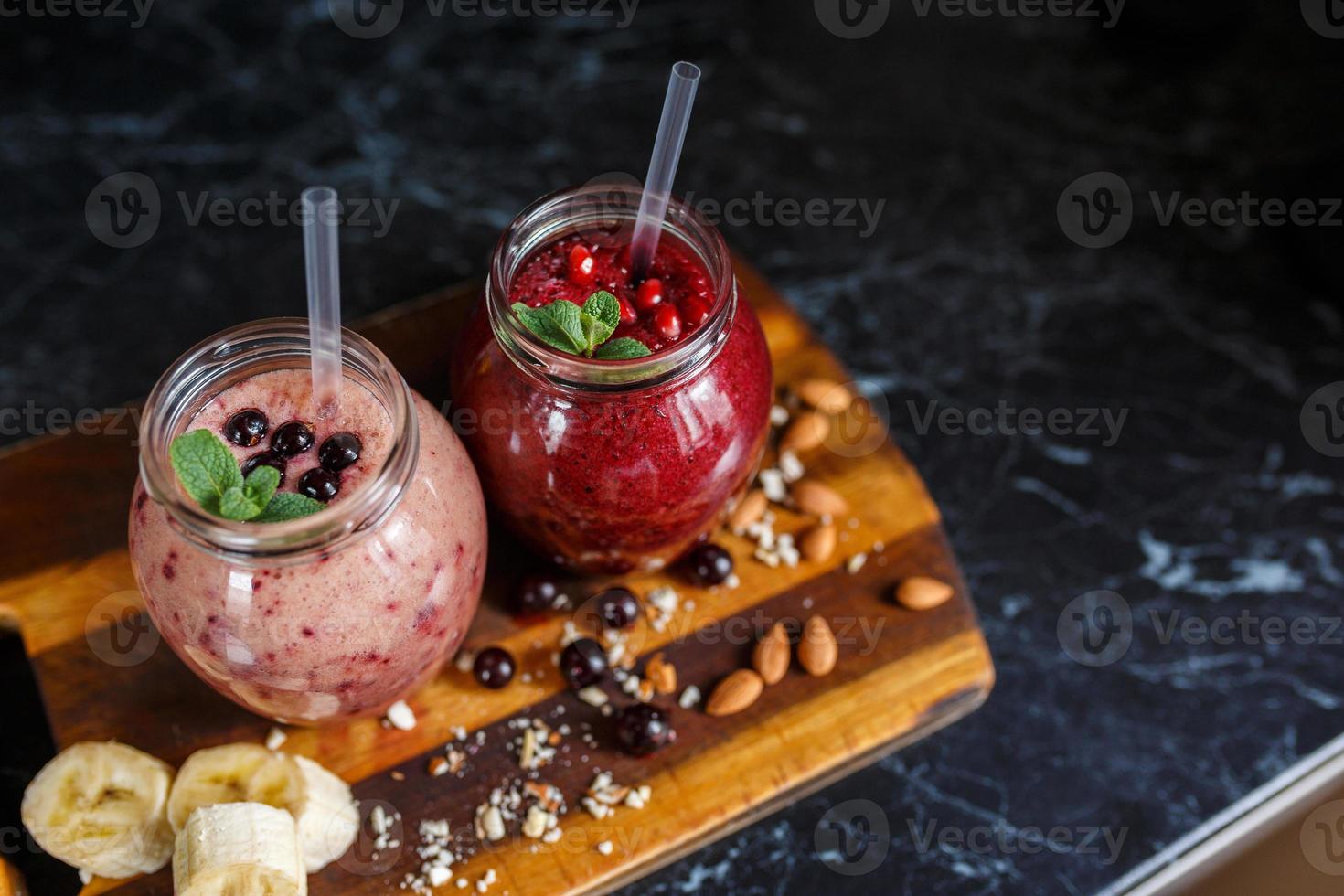 batidos recién preparados de plátano con granada y plátano con mora en botella. dieta, estilo de vida saludable foto