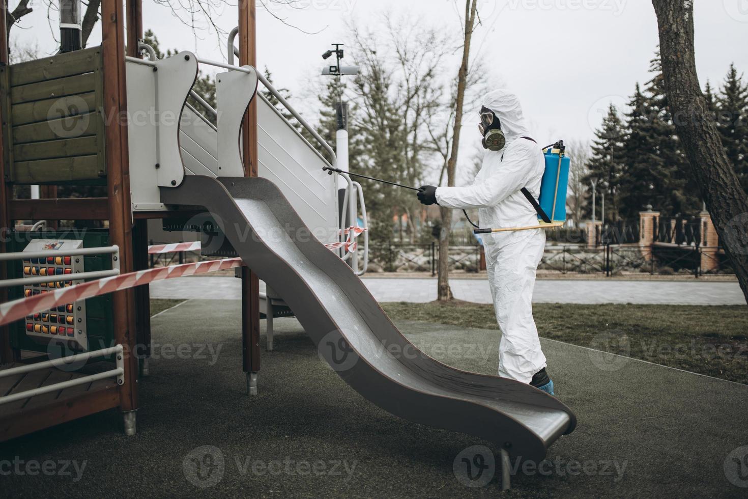 Cleaning and Disinfection on the playground in the sity complex amid the coronavirus epidemic Teams for disinfection efforts Infection prevention and control of epidemic Protective suit and mask photo