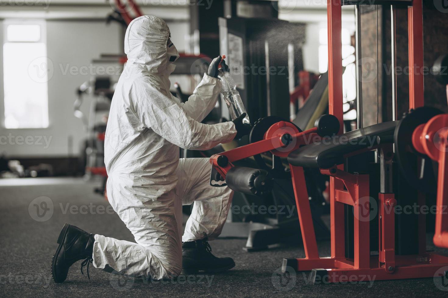 Cleaning and Disinfection in crowded places amid the coronavirus epidemic Gym cleaning and disinfection Infection prevention and control of epidemic. Protective suit and mask and spray bag photo