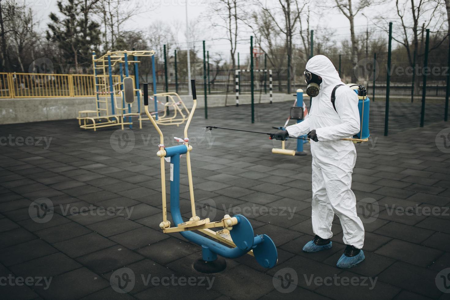 Cleaning and Disinfection on the playground in the sity complex amid the coronavirus epidemic Teams for disinfection efforts Infection prevention and control of epidemic Protective suit and mask photo