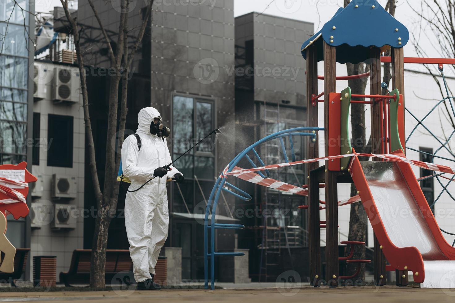 Cleaning and Disinfection on the playground in the sity complex amid the coronavirus epidemic Teams for disinfection efforts Infection prevention and control of epidemic Protective suit and mask photo