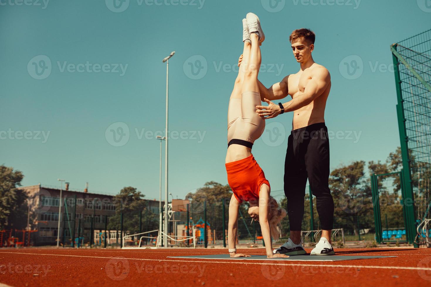 joven rubia aprende a mantener el equilibrio en una parada de cabeza y de manos foto