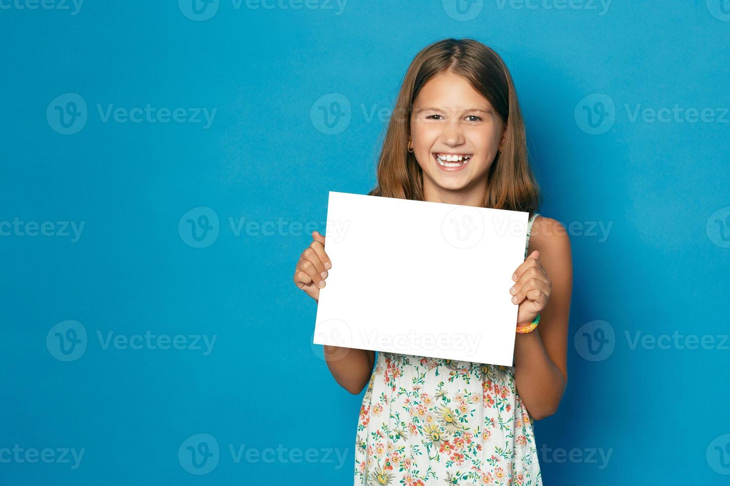 hermosa niña sonriente con dientes blancos sosteniendo en las manos espacio en blanco para el anuncio foto