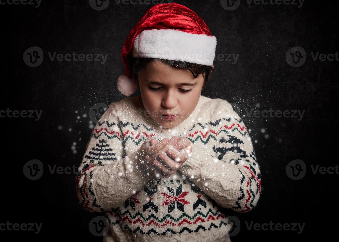 little child blows snow from hands in christmas photo