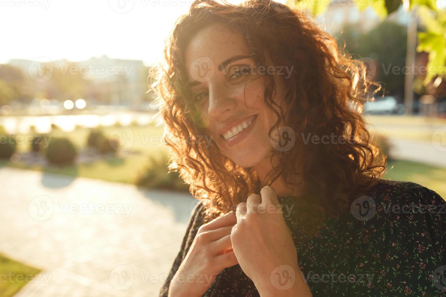 Portraits of a charming red-haired girl with freckles and a pretty face. The girl poses for the camera in the city center. She has a great mood and a sweet smile photo