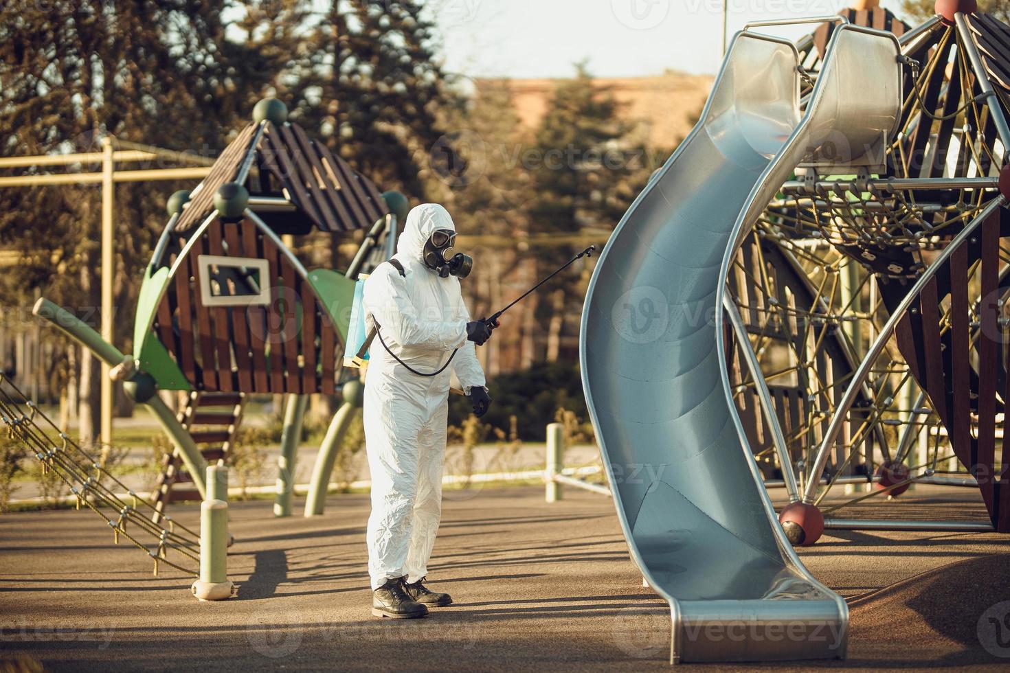 Cleaning and Disinfection on the playground in the sity complex amid the coronavirus epidemic Teams for disinfection efforts Infection prevention and control of epidemic Protective suit and mask photo