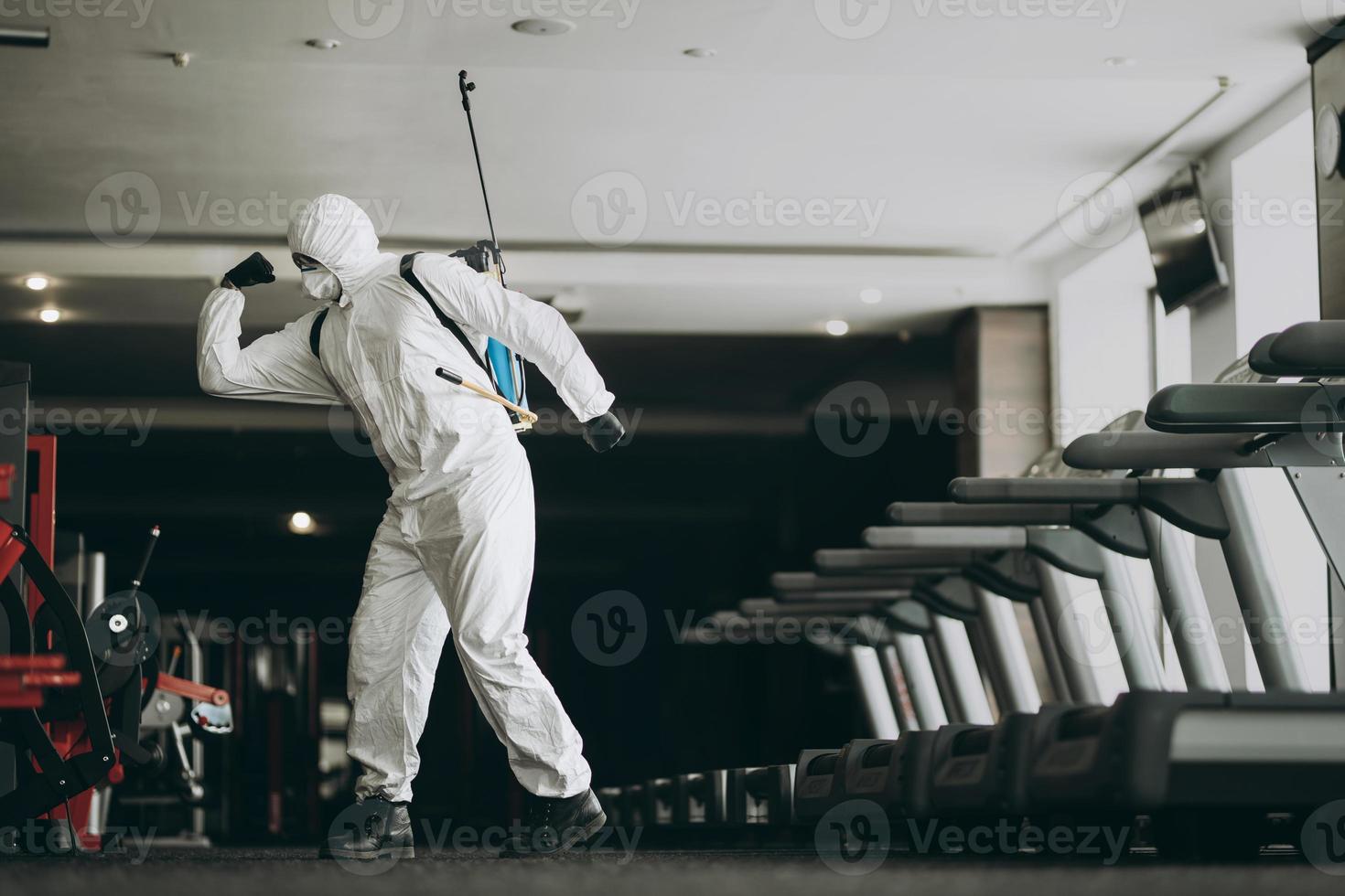 Cleaning and Disinfection in crowded places amid the coronavirus epidemic Gym cleaning and disinfection Infection prevention and control of epidemic. Protective suit and mask and spray bag photo