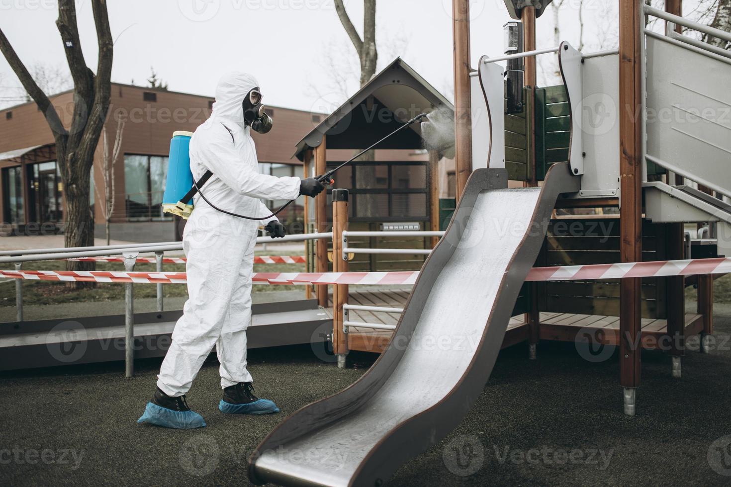 Cleaning and Disinfection on the playground in the sity complex amid the coronavirus epidemic Teams for disinfection efforts Infection prevention and control of epidemic Protective suit and mask photo