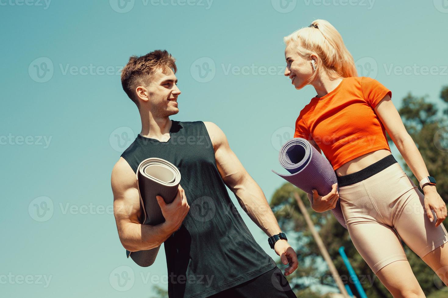 young couple walking down the street with sports mats in their hands photo