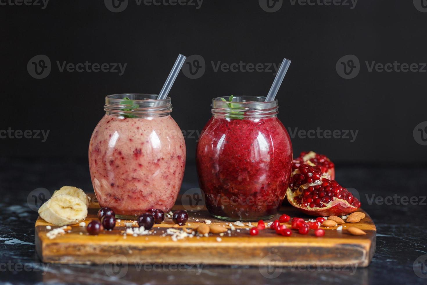 batidos recién preparados de plátano con granada y plátano con mora en botella. dieta, estilo de vida saludable foto