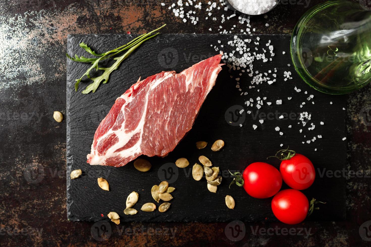 raw pork with spices for cooking on a fire or oven on a dark stone background photo