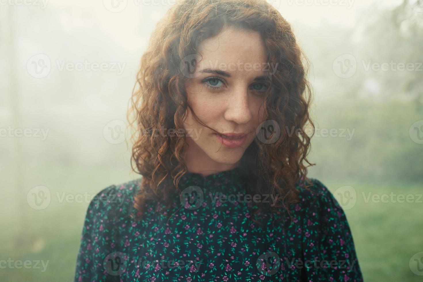 cute red-haired curly girl rejoices under the water fogger in the city center photo