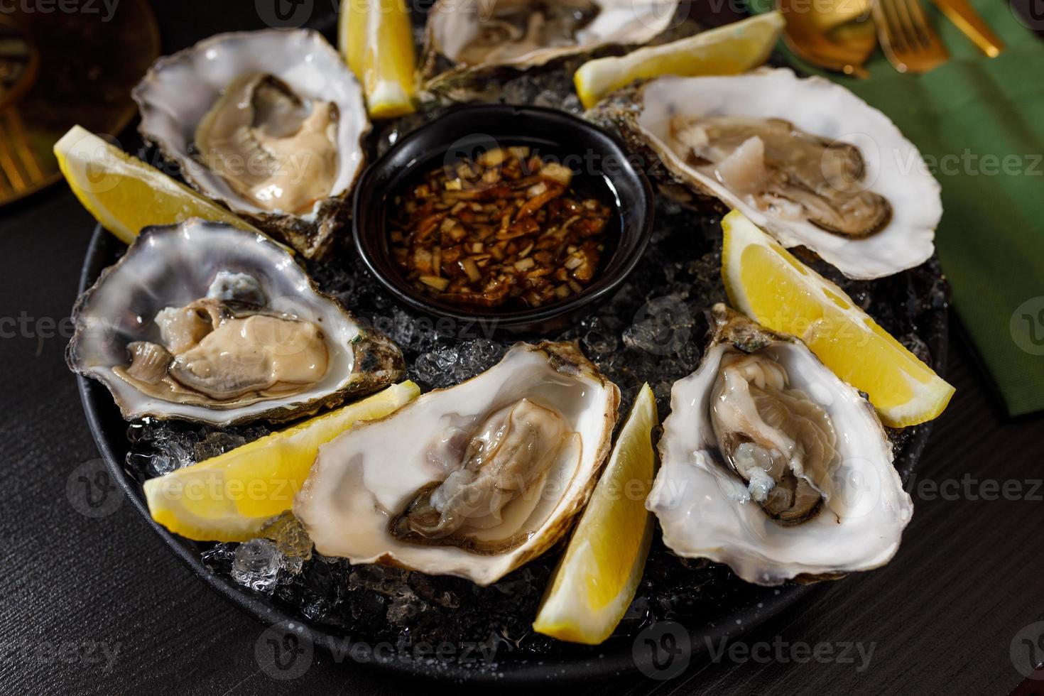 open fresh oysters on a metal plate in ice on a concrete background photo