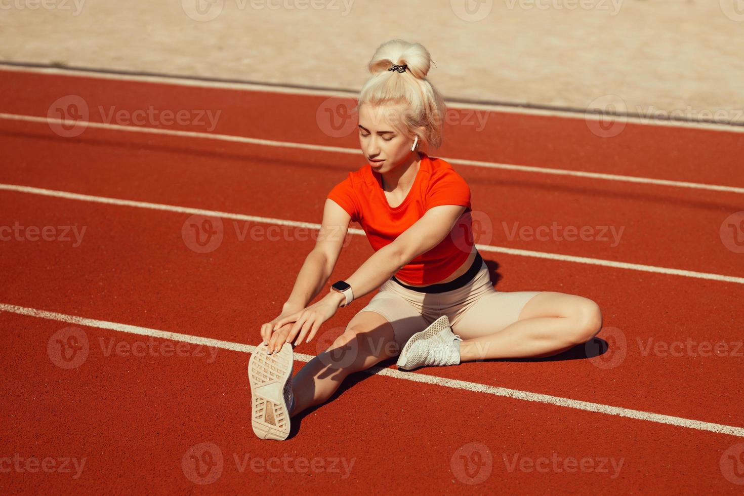 young beautiful girl doing warm-up before sports exercise at school stadium photo