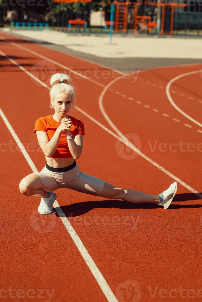 young beautiful girl doing warm-up before sports exercise at school stadium photo