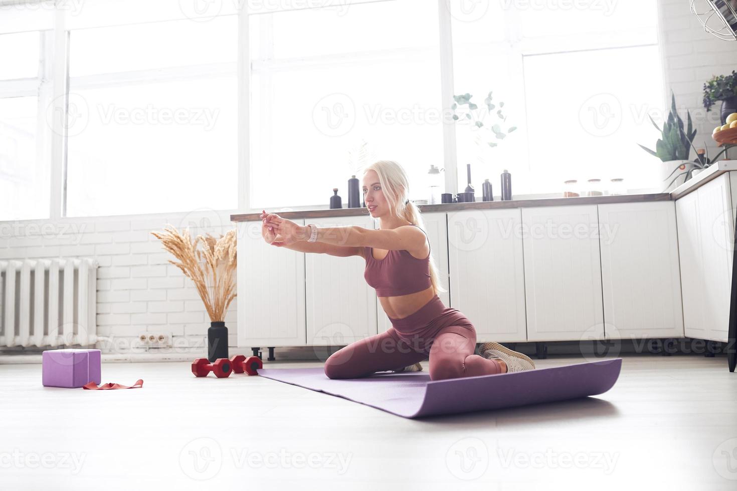 young beautiful blonde takes care of her body while at home during quarantine. She trains people online through her mobile phone photo