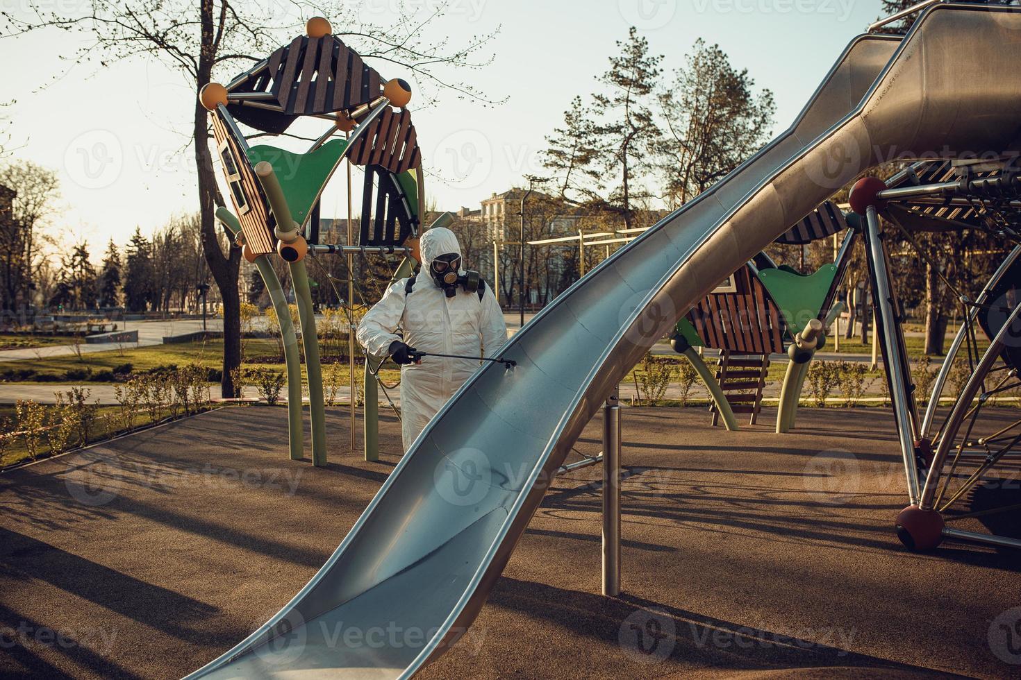 Cleaning and Disinfection on the playground in the sity complex amid the coronavirus epidemic Teams for disinfection efforts Infection prevention and control of epidemic Protective suit and mask photo