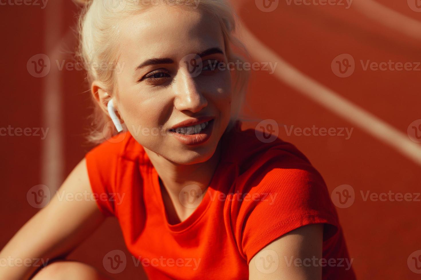 close-up portrait of a beautiful blonde who is sitting on a jogging track photo
