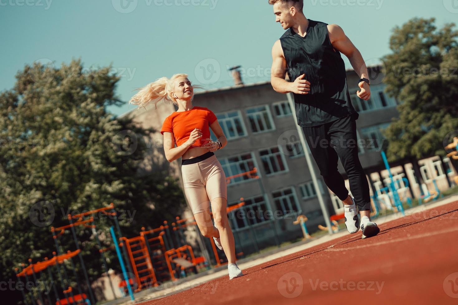 Young sports couple running in the stadium on the running track photo