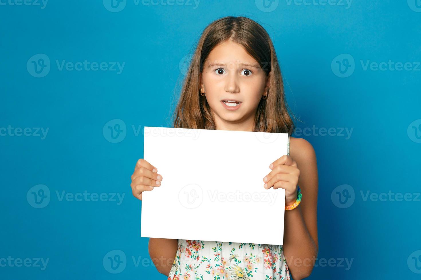 beautiful smiling child  girl with white teeth holding in hands white blank copy space for the announcement photo