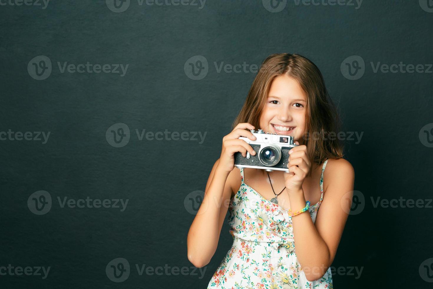 hermosa niña sonriente con dientes blancos sosteniendo una cámara instantánea foto