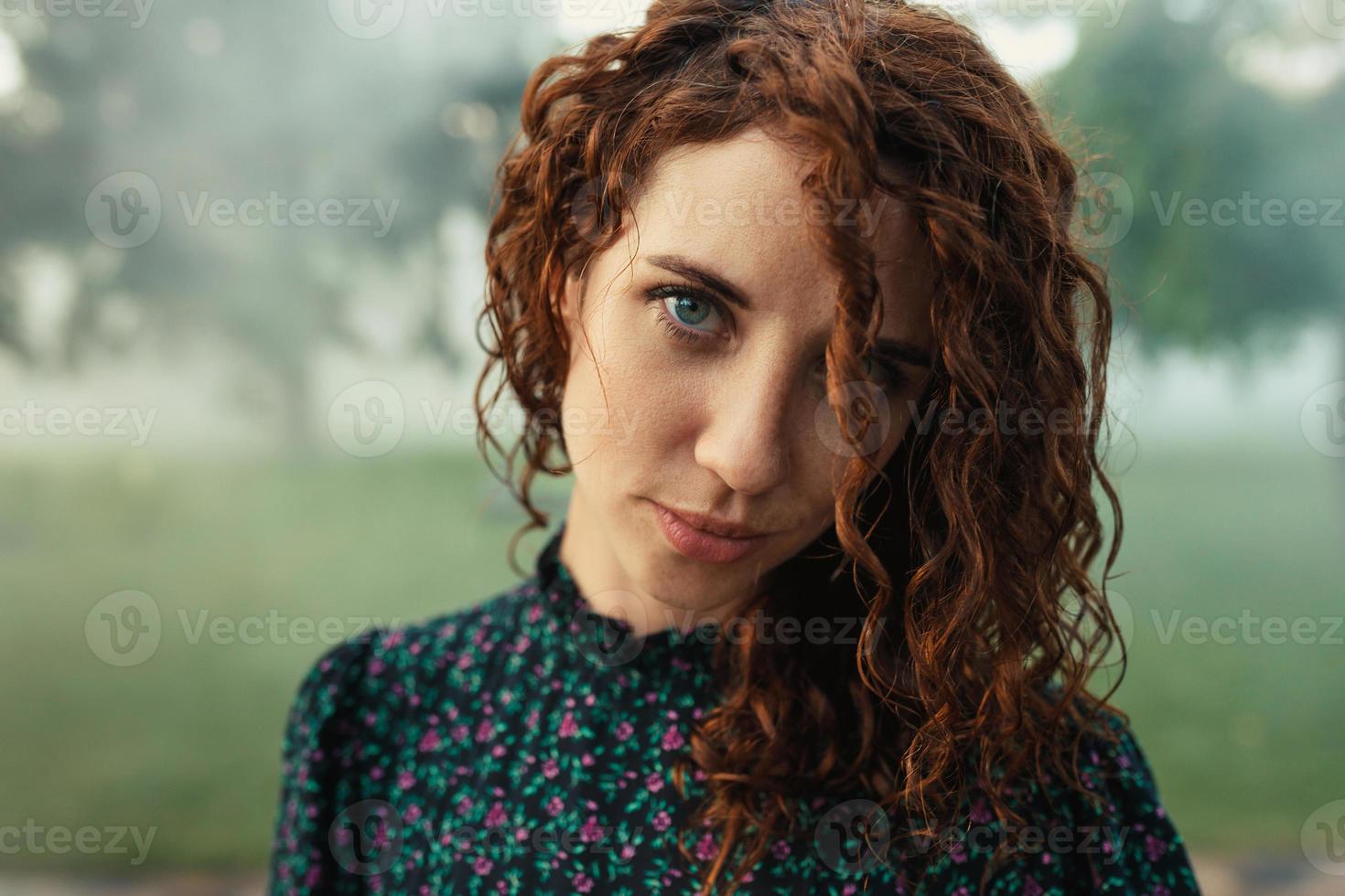 cute red-haired curly girl rejoices under the water fogger in the city center photo