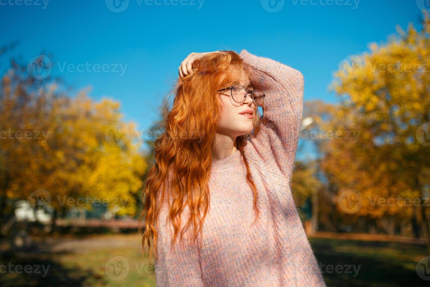 retratos de una encantadora chica pelirroja con una cara linda. chica posando en el parque de otoño con un suéter y una falda de color coral. la niña tiene un estado de ánimo maravilloso foto