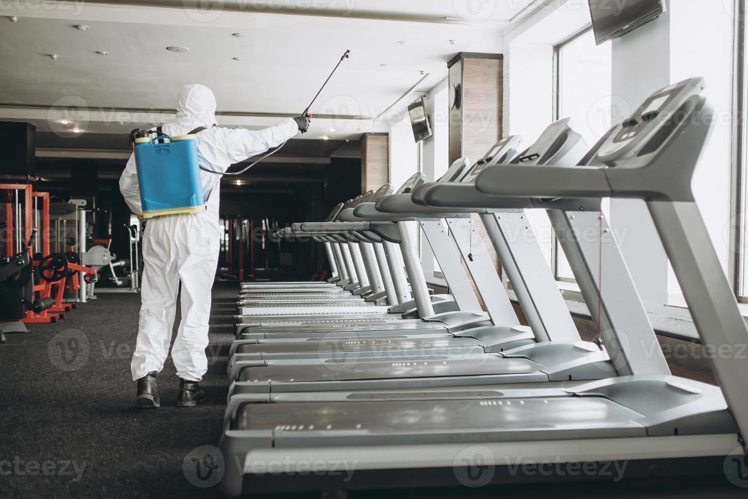 limpieza y desinfección en lugares concurridos en medio de la epidemia de coronavirus limpieza y desinfección de gimnasios prevención de infecciones y control de epidemias. traje de protección y máscara y bolsa de spray foto