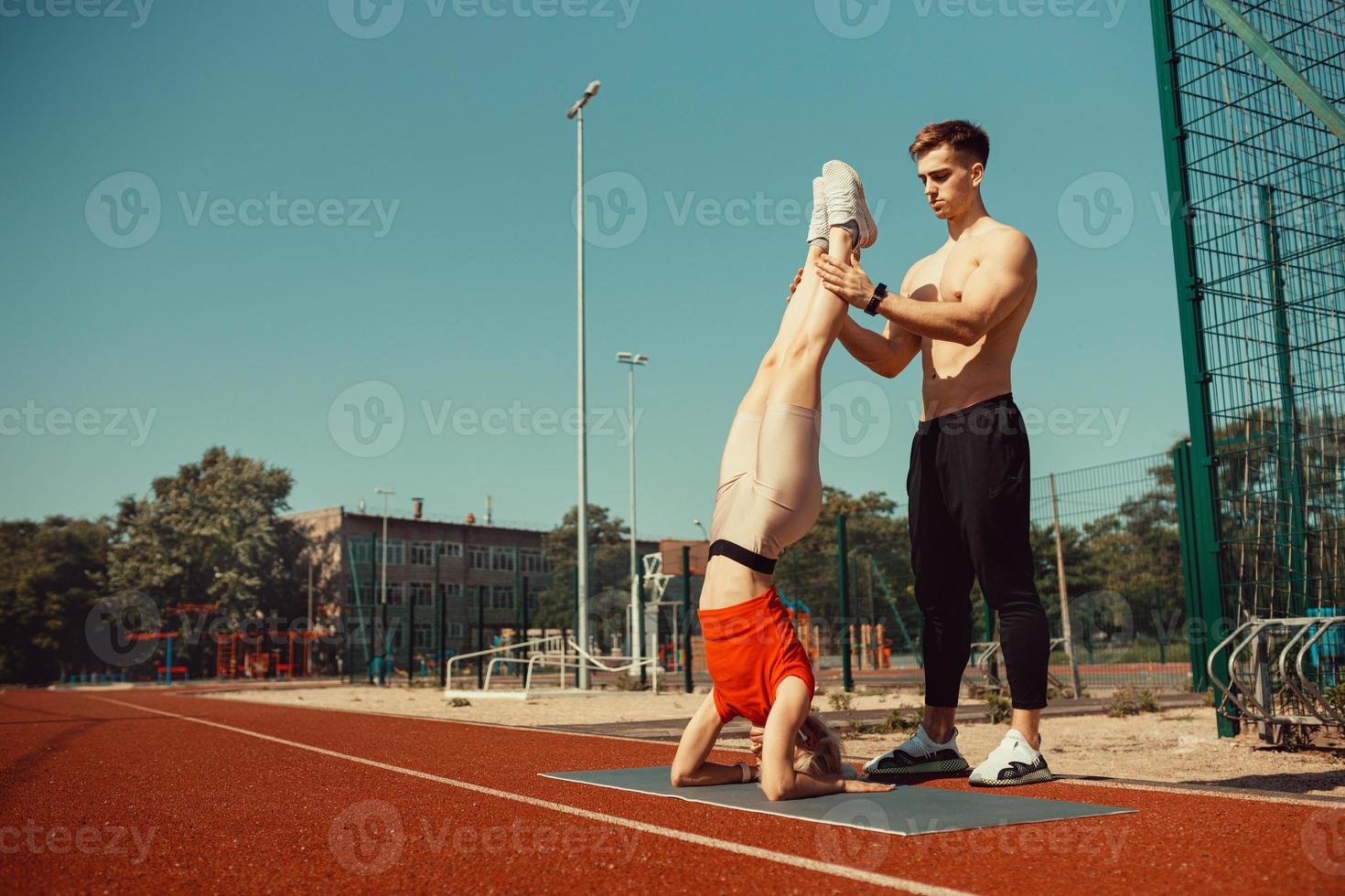 joven rubia aprende a mantener el equilibrio en una parada de cabeza y de manos foto