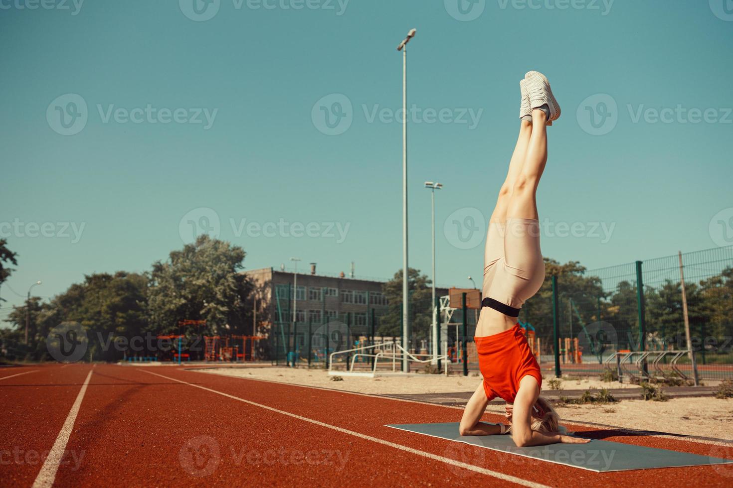 joven rubia aprende a mantener el equilibrio en una parada de cabeza y de manos foto