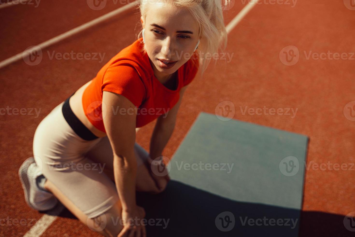 close-up portrait of a beautiful blonde who is sitting on a jogging track photo