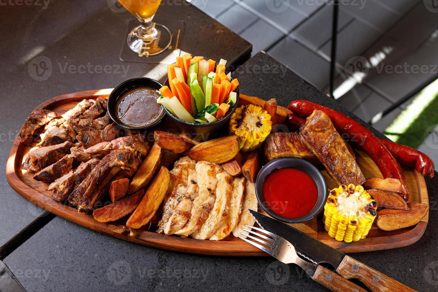 Josper set of pork ribs, chicken fillet, ribeye steak, hunting sausages, corn, potatoes and fresh vegetables photo