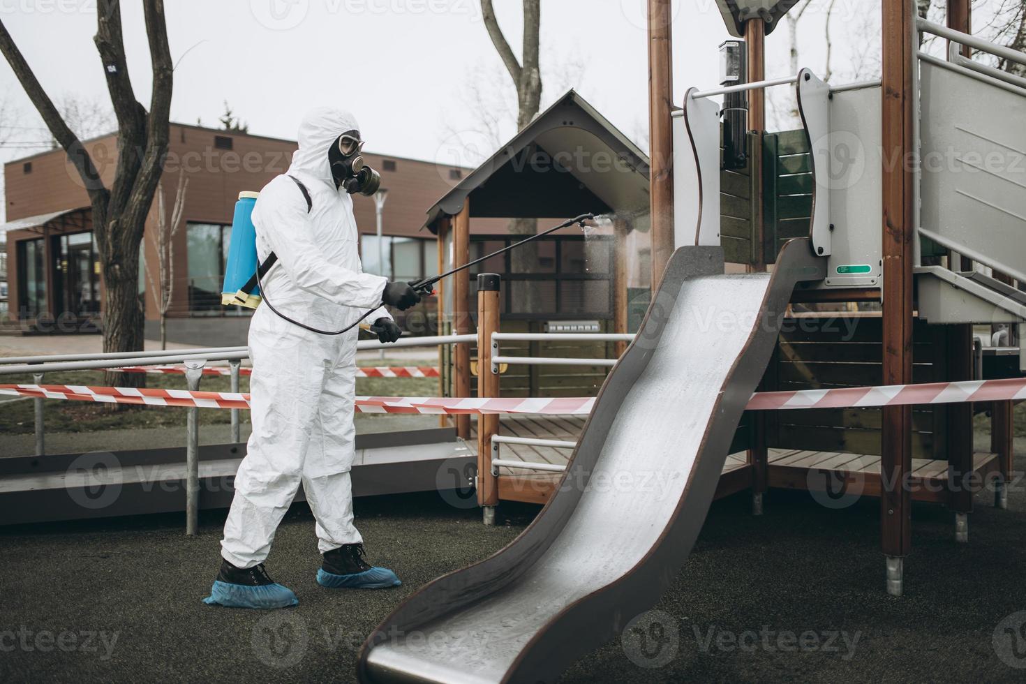 Cleaning and Disinfection on the playground in the sity complex amid the coronavirus epidemic Teams for disinfection efforts Infection prevention and control of epidemic Protective suit and mask photo