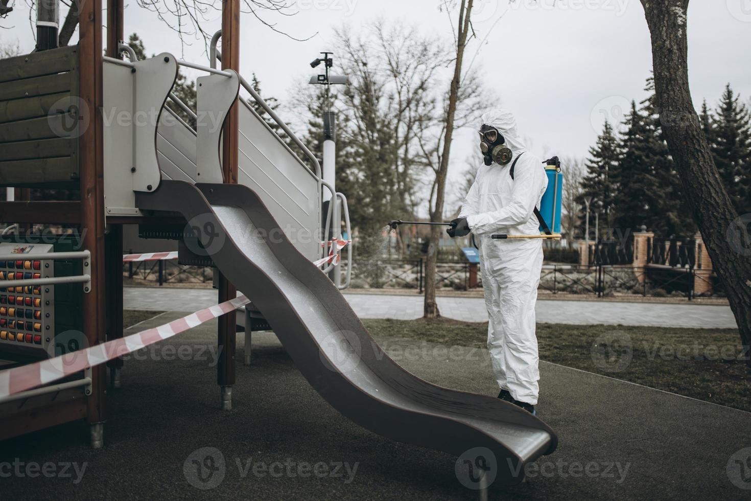 Cleaning and Disinfection on the playground in the sity complex amid the coronavirus epidemic Teams for disinfection efforts Infection prevention and control of epidemic Protective suit and mask photo